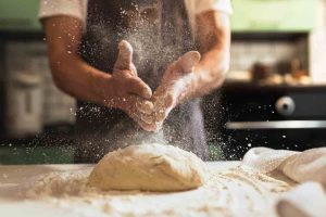 man hands brushing flour on bread