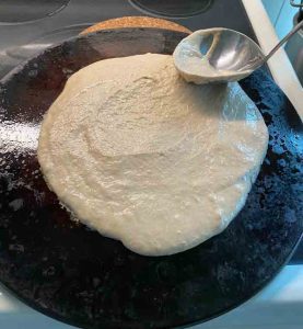 ladel smoothing dough on pan