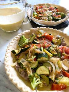 unbaked pie crusts with vegetables before pouring the egg mixture 